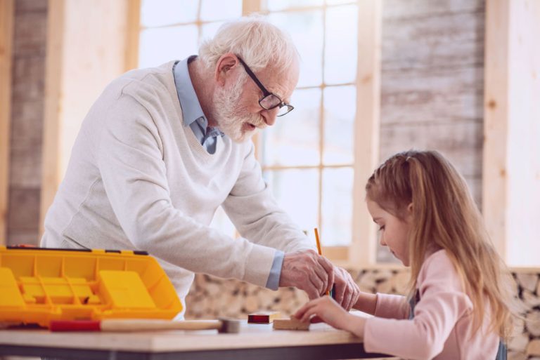 une personne âgée qui aide une enfant à dessiner