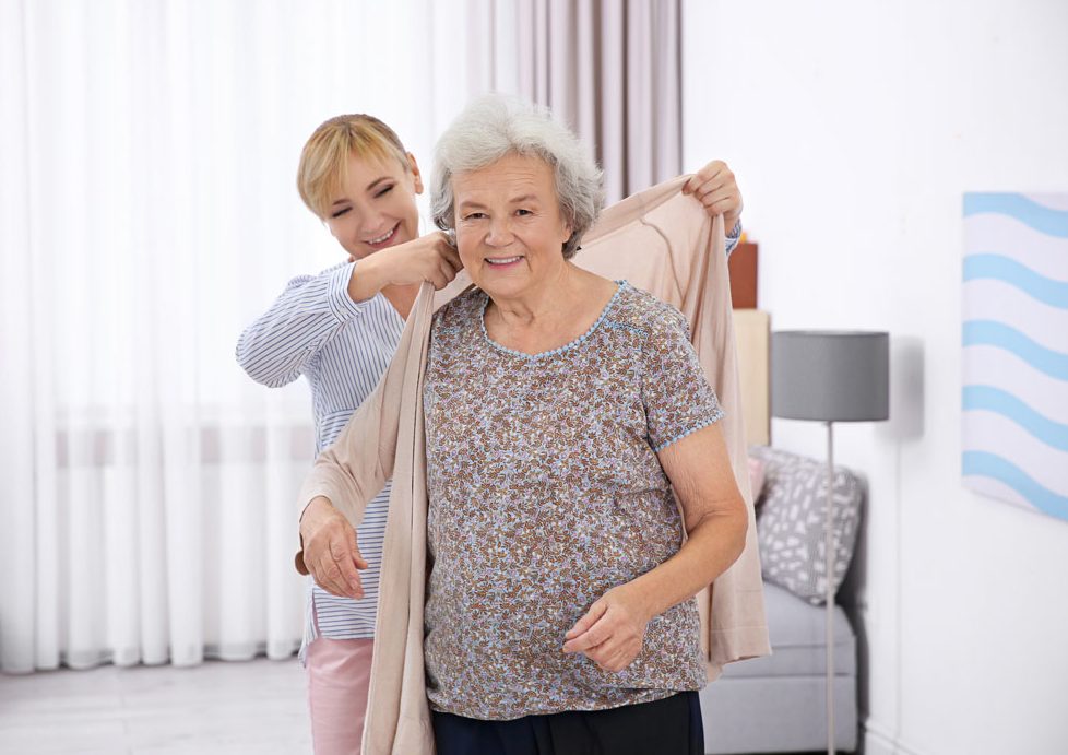 une dame qui aide un senior à mettre son gilet