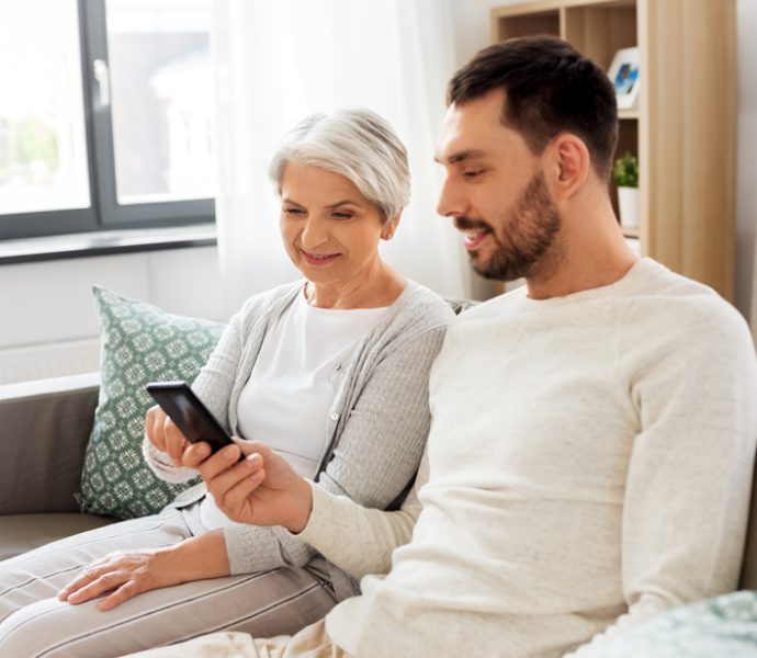 un jeune homme et une personne âgée qui consultent ensemble un téléphone