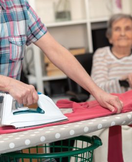 une dame qui fait le repassage et une personne âgée la regarde