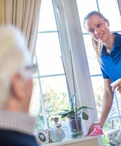 une dame qui fait le ménage et un senior qui la regarde