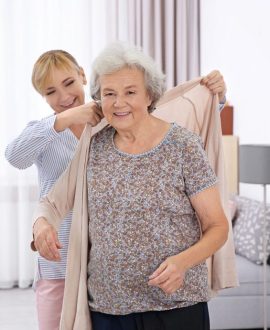 une dame qui aide un senior à mettre son gilet