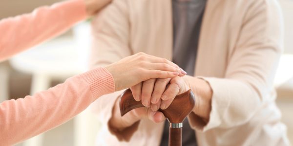 une dame qui tient la main à une personne âgée